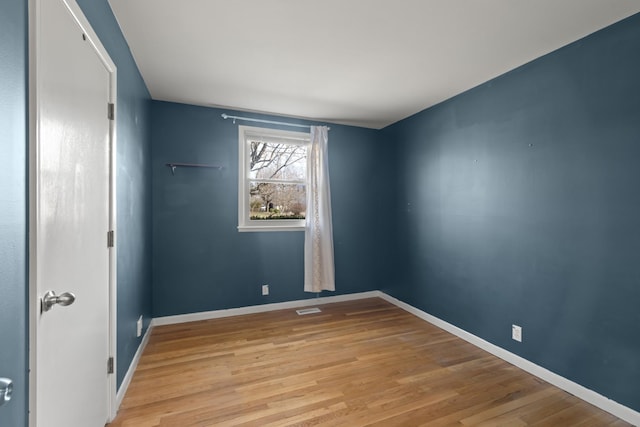 empty room with baseboards, visible vents, and light wood finished floors