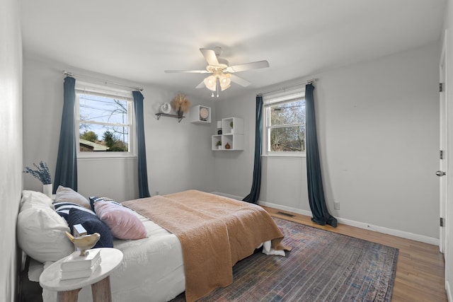 bedroom with visible vents, ceiling fan, baseboards, and wood finished floors