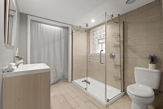 full bath with wood finish floors, a stall shower, vanity, and toilet