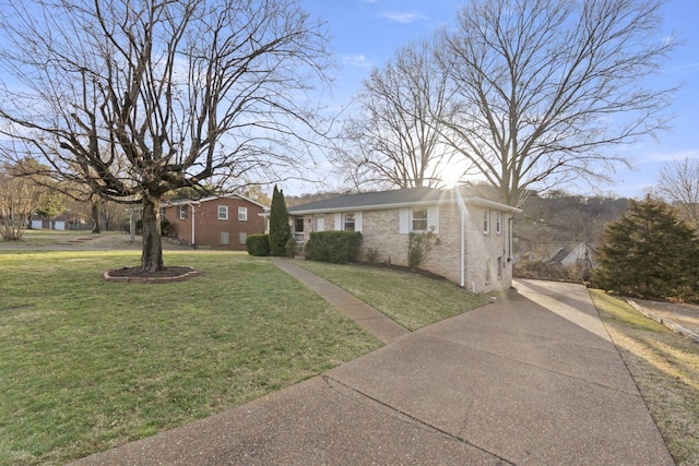 view of front of home with driveway, brick siding, and a front yard