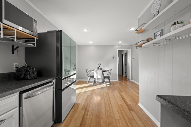 kitchen featuring dark countertops, light wood finished floors, open shelves, and stainless steel appliances