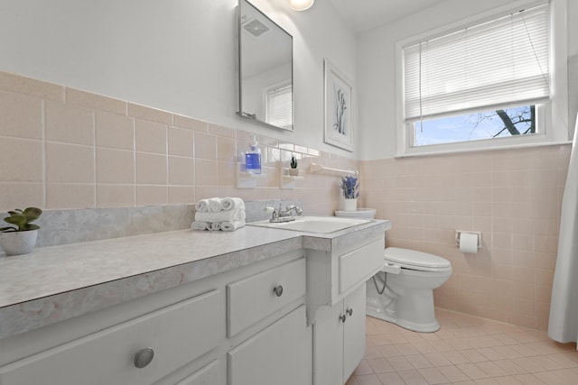 bathroom featuring tile walls, toilet, wainscoting, vanity, and tile patterned floors