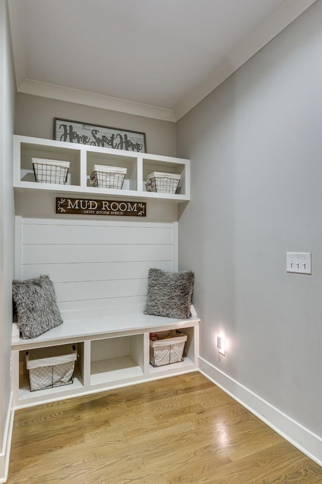 mudroom with crown molding, baseboards, and wood finished floors