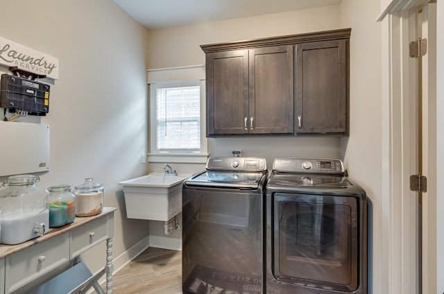 washroom with washer and clothes dryer, light wood finished floors, cabinet space, a sink, and baseboards