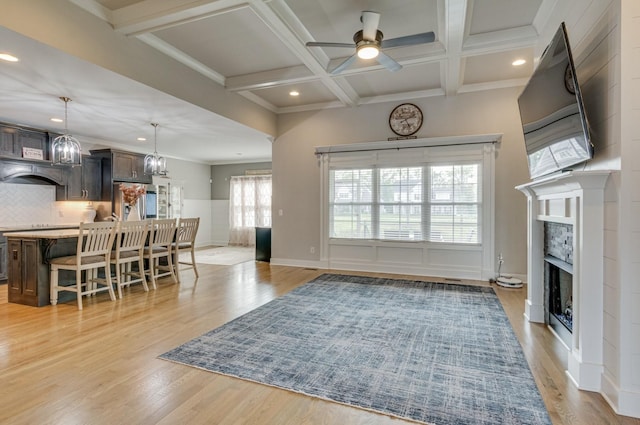 living area with beam ceiling, coffered ceiling, a fireplace, and light wood-style flooring