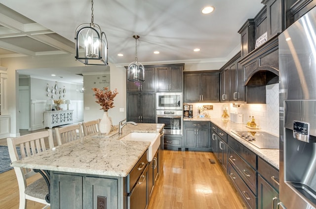 kitchen with appliances with stainless steel finishes, a sink, light wood-style flooring, and a kitchen breakfast bar