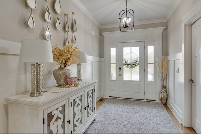 foyer featuring light wood-style floors, ornamental molding, a decorative wall, and a wainscoted wall