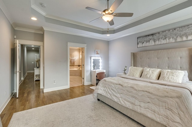 bedroom featuring ornamental molding, a tray ceiling, wood finished floors, and baseboards