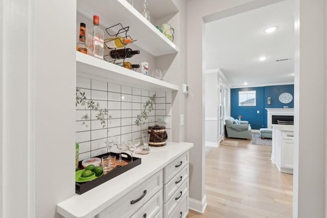 bar featuring tasteful backsplash, visible vents, baseboards, light wood-style flooring, and a fireplace