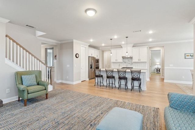 kitchen featuring a breakfast bar area, visible vents, appliances with stainless steel finishes, open floor plan, and white cabinets