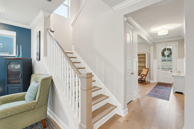 staircase featuring visible vents, crown molding, baseboards, and wood finished floors