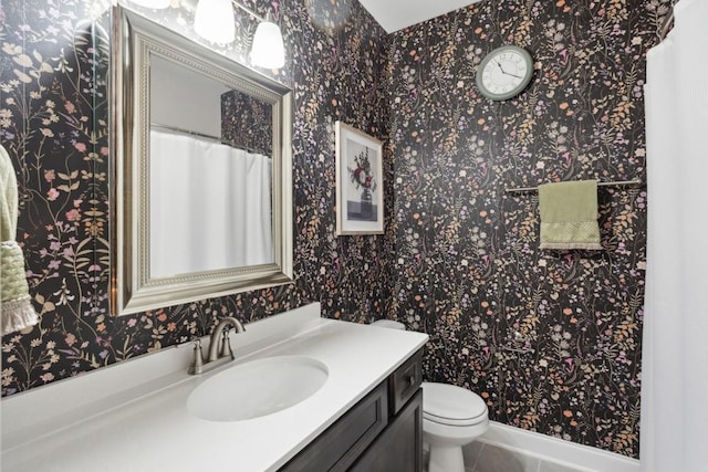 full bath with toilet, tile patterned floors, vanity, and wallpapered walls