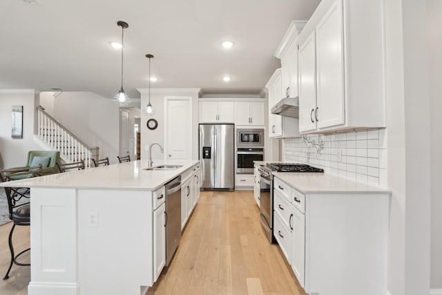 kitchen with stainless steel appliances, a breakfast bar, white cabinets, and under cabinet range hood