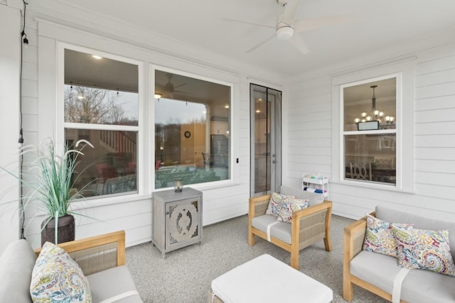 sunroom / solarium featuring ceiling fan with notable chandelier