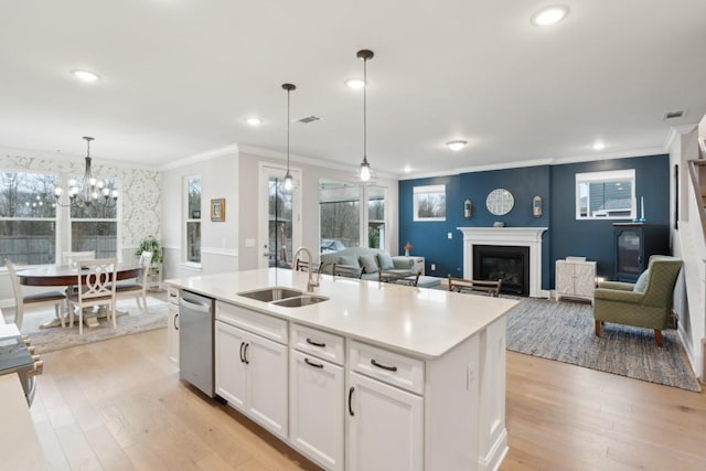 kitchen featuring visible vents, dishwasher, a glass covered fireplace, light wood-style flooring, and a sink