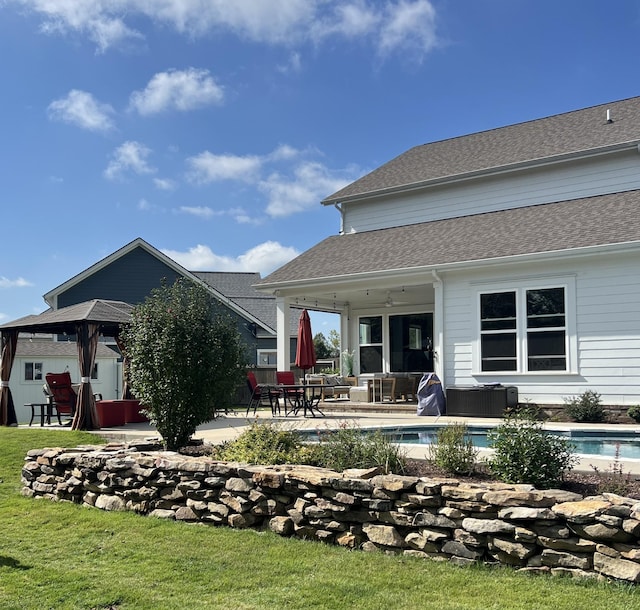 rear view of property with a patio, a shingled roof, and an outdoor pool