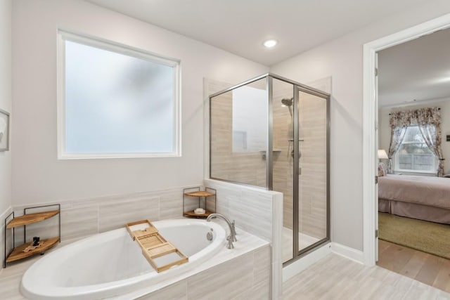 bathroom featuring wood finished floors, ensuite bath, a shower stall, and a bath