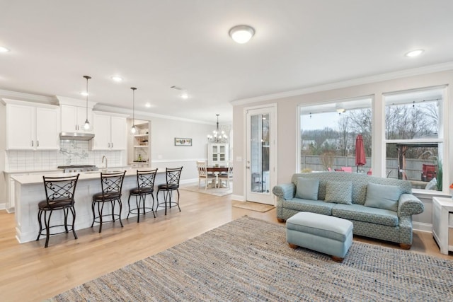 living area featuring baseboards, light wood-style floors, recessed lighting, and crown molding