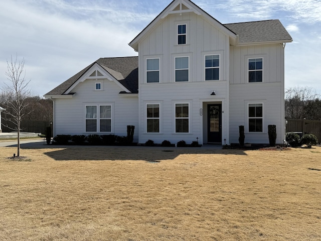 view of front of property with a front yard, board and batten siding, and roof with shingles