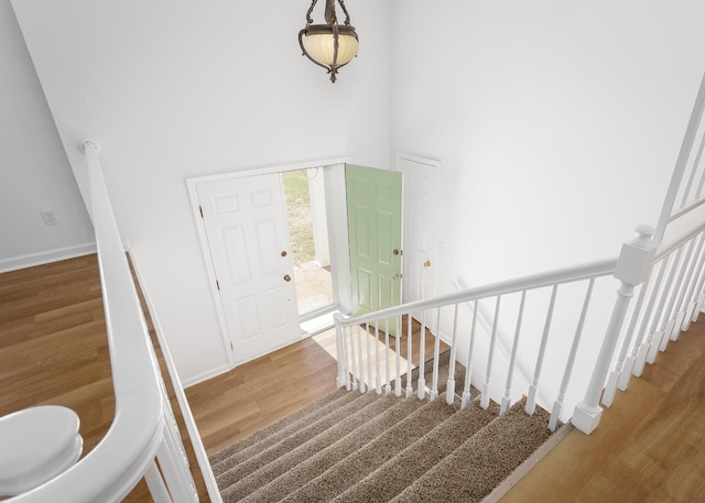 foyer entrance featuring stairway, wood finished floors, a towering ceiling, and baseboards