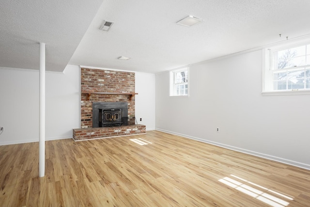 unfurnished living room with a textured ceiling, wood finished floors, visible vents, and baseboards