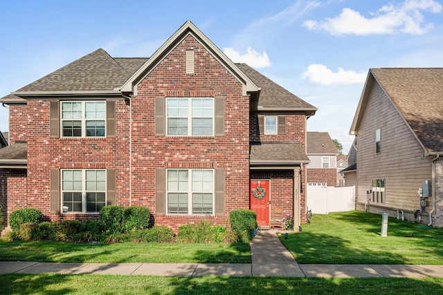 traditional-style house with brick siding, a shingled roof, and fence