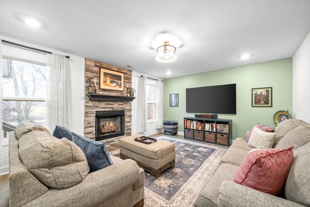 living room featuring a fireplace, plenty of natural light, baseboards, and wood finished floors