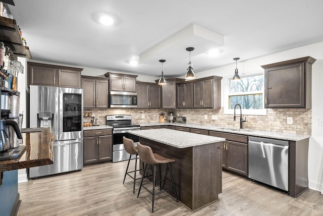 kitchen featuring appliances with stainless steel finishes, a sink, dark brown cabinetry, and light wood-style floors