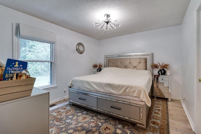 bedroom with baseboards, a textured ceiling, a chandelier, and wood finished floors