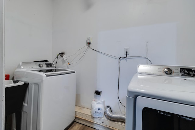 washroom with laundry area, wood finished floors, a sink, and independent washer and dryer