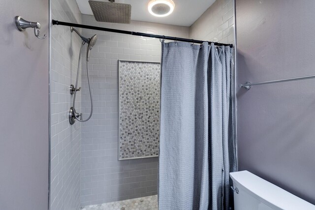 bathroom with a shower stall and toilet