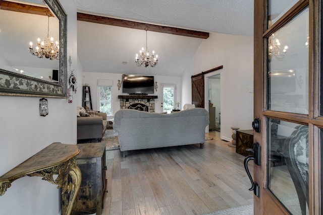 living area with a chandelier, light wood-style flooring, lofted ceiling with beams, and a barn door