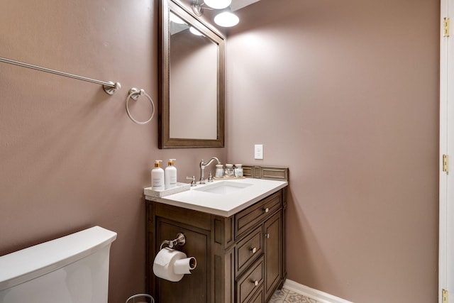 half bath featuring vanity, toilet, and baseboards