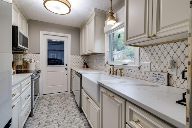 kitchen with stainless steel appliances, backsplash, a sink, a textured ceiling, and light stone countertops