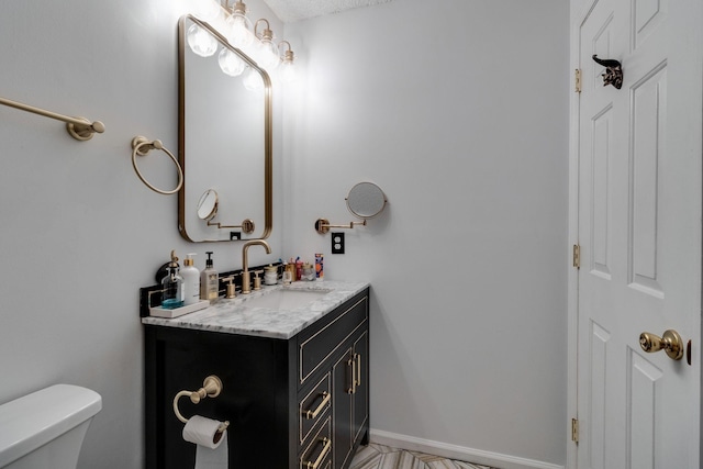 half bathroom featuring toilet, vanity, and baseboards