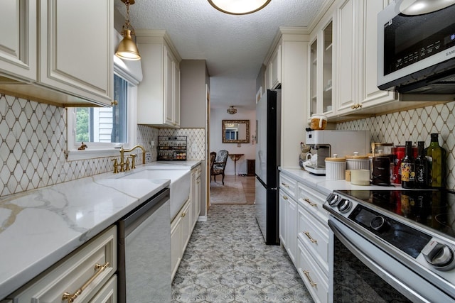 kitchen featuring tasteful backsplash, glass insert cabinets, decorative light fixtures, stainless steel appliances, and a sink