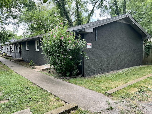 view of home's exterior featuring brick siding and a yard