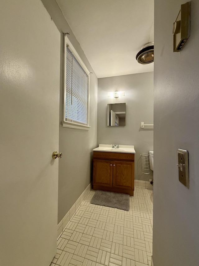 bathroom featuring toilet, baseboards, and vanity