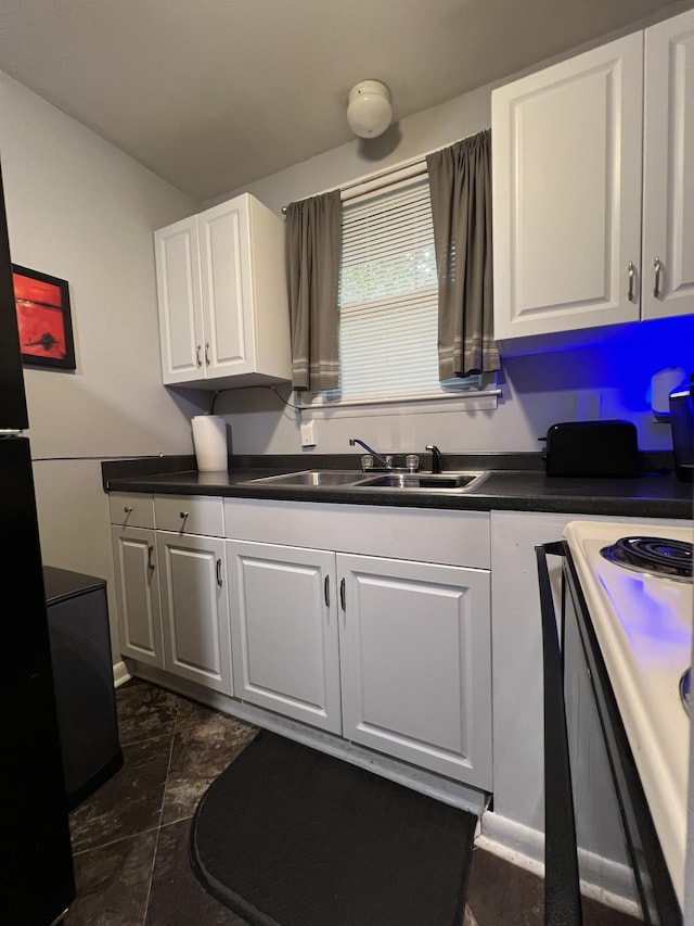 kitchen with a sink, dark countertops, white cabinets, and electric range oven