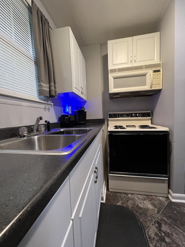 kitchen featuring white microwave, range with electric stovetop, a sink, white cabinets, and dark countertops