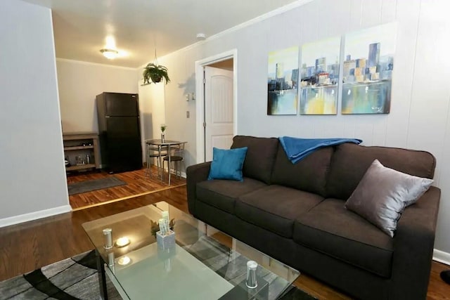 living room featuring crown molding, baseboards, and wood finished floors