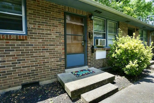 property entrance with brick siding and cooling unit