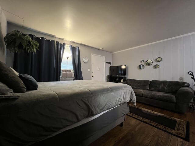 bedroom with ornamental molding and wood finished floors