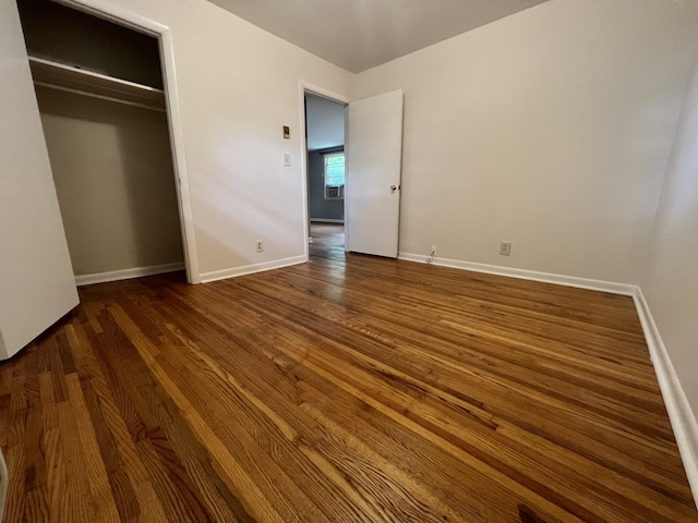 unfurnished bedroom with a closet, baseboards, and wood finished floors