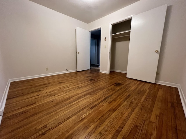 unfurnished bedroom featuring a closet, hardwood / wood-style flooring, and baseboards