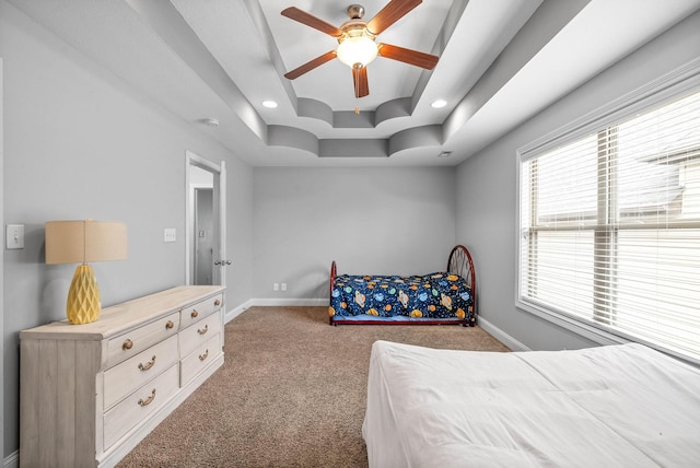 bedroom with carpet floors, baseboards, a raised ceiling, and a ceiling fan