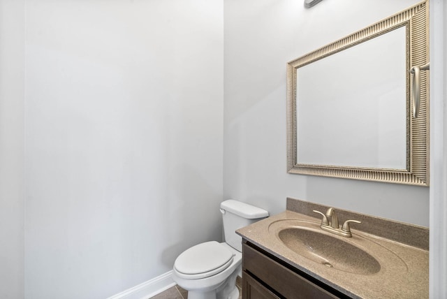 half bath featuring toilet, baseboards, and vanity