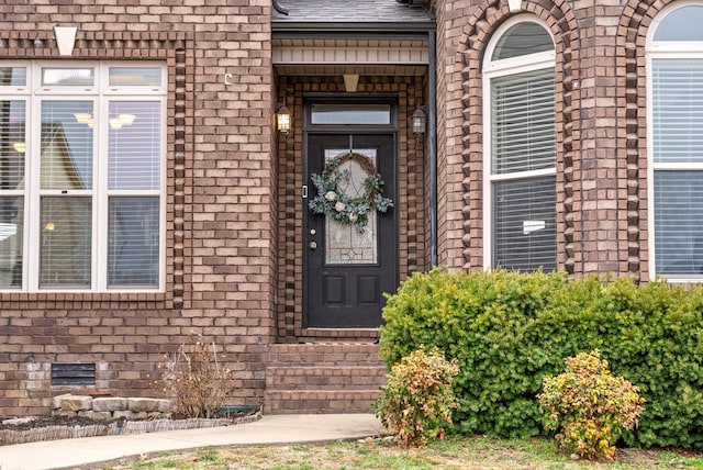 doorway to property with brick siding and roof with shingles