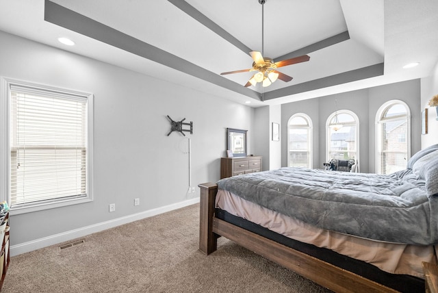 carpeted bedroom with baseboards, visible vents, a raised ceiling, a ceiling fan, and recessed lighting