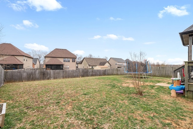 view of yard with a trampoline, a fenced backyard, and a residential view